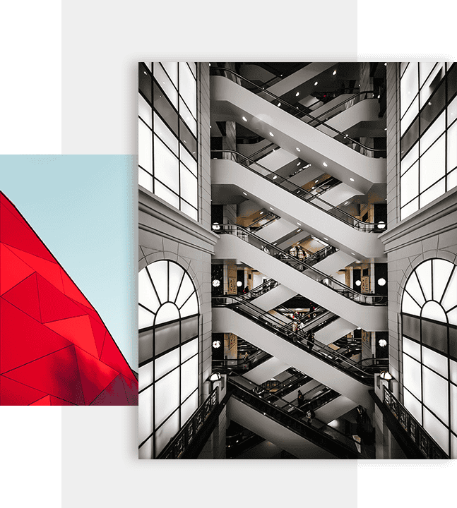 Spiral escalator inside modern shopping mall with large arched windows and sleek design.