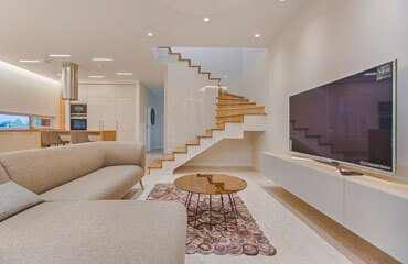 A modern living room with stairs and a tv.